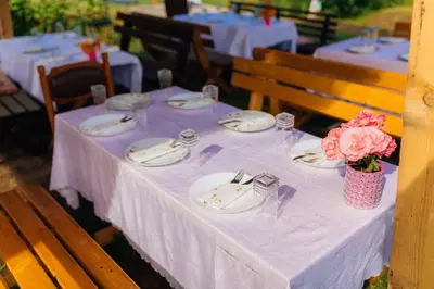 a table with plates and a vase of flowers on it at Camp Podkraj in Virpazar