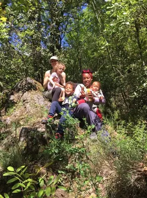 a man and three children sitting on a rock at Camp Podkraj in Virpazar