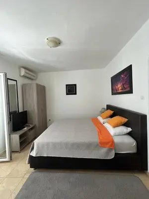 a bedroom with a bed with orange pillows and a television at Apartmani Kažanegra33 in Pržno