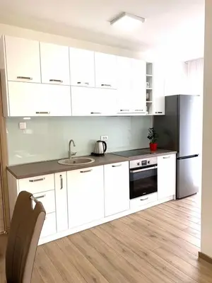 a kitchen with white cabinets and a sink and a refrigerator at Apartmani Kažanegra33 in Pržno