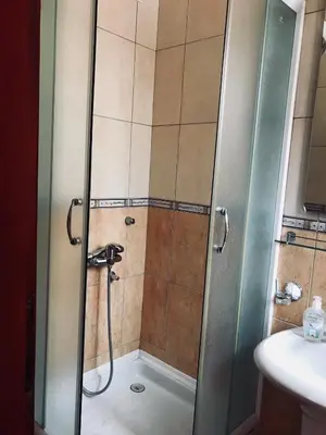a shower with a glass door next to a sink at Apartmani Kažanegra33 in Pržno
