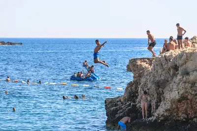 a group of people jumping off a cliff into the water at Miracle in Budva