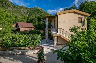 a house with a staircase in front of a yard at Ethno Lodge AB in Virpazar