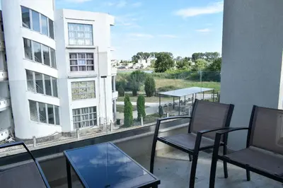 a balcony with chairs and tables and a building at Lux Kalimera Apartments in Ulcinj