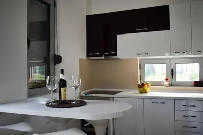 a white kitchen with a white table with wine glasses at Lux Kalimera Apartments in Ulcinj