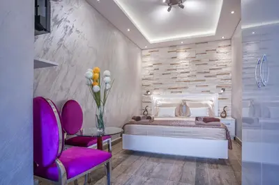 a bedroom with a bed and two purple chairs at Luxury Boutique Studio Apartments in Budva