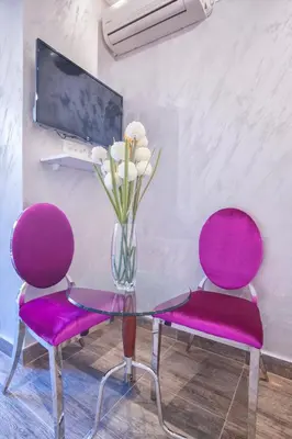 a glass table with two purple chairs and a vase of flowers at Luxury Boutique Studio Apartments in Budva