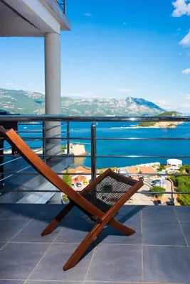 a wooden chair sitting on a balcony overlooking the water at Vidikovac Marble House in Budva