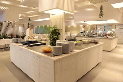 a kitchen with two chefs preparing food in a restaurant at Hotel Castellastva in Petrovac na Moru