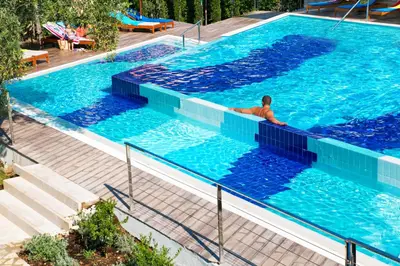 a man is sitting in a swimming pool at Hotel Castellastva in Petrovac na Moru