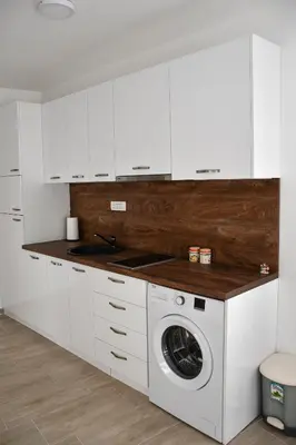 a kitchen with white cabinets and a washing machine at Raj in Kotor