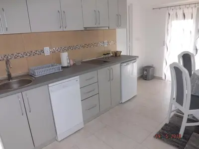 a kitchen with white cabinets and a sink and a chair at Raj in Kotor
