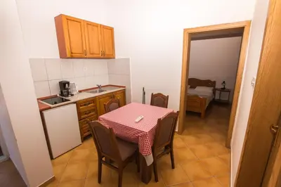 a small kitchen with a table with chairs and a sink at Apartments De Lara in Utjeha