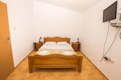 a bedroom with a bed and a flat screen tv at Apartments De Lara in Utjeha