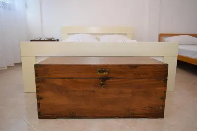 a white bed with a wooden chest in a bedroom at Apartment Monika in Kotor