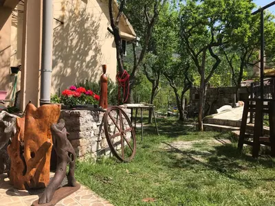 a garden with a statue of a wheel next to a house at Guest house Duletic in Budva