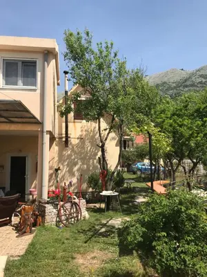 a house with a table and a tree in the yard at Guest house Duletic in Budva