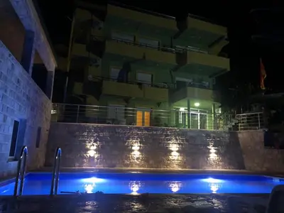 a swimming pool in front of a building at night at Apartments Bibic in Budva
