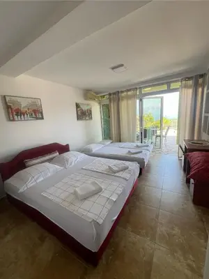 a bedroom with three beds and a balcony at Apartments Bibic in Budva