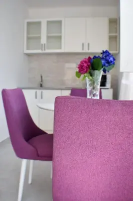 a purple chair and a vase of flowers on a table at Apartmani Ognjanovic Kotor in Kotor