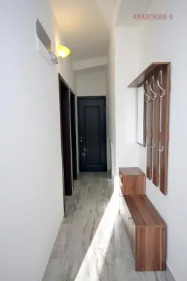 a hallway with a black door and a wooden bench at Apartments Kojic in Bar