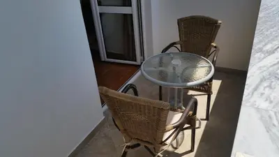 a glass table and two chairs in a room at Apartments Kojic in Bar