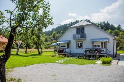 a white house with a balcony and a yard at Apartments Heaven in Cetinje