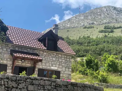 a stone house with a mountain in the background at Lovcen Holiday Home in Cetinje