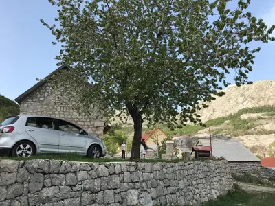 a silver car parked next to a stone wall at Lovcen Holiday Home in Cetinje