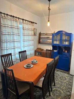 a dining room table with chairs and a blue cabinet at Lovcen Holiday Home in Cetinje
