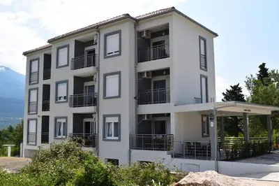 a white building with balconies and an umbrella at Kristina Apartments in Tivat