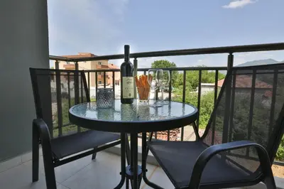 a table with a bottle of wine and two chairs on a balcony at Kristina Apartments in Tivat