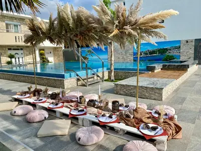 a group of people sitting at a table in front of a pool at Blue Star Apartments in Ulcinj