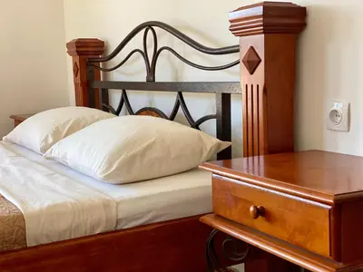 a bed with a wooden headboard next to a wooden table at Blue Star Apartments in Ulcinj