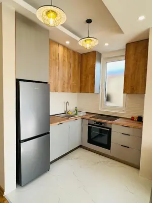 a kitchen with a stainless steel refrigerator and wooden cabinets at Apartment Luxury Explorer in Podgorica