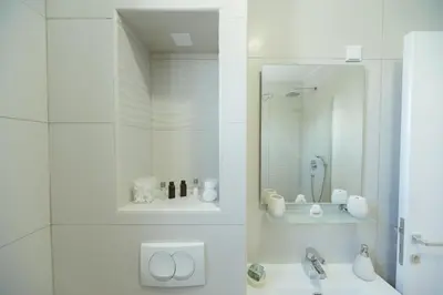 a white bathroom with a sink and a mirror at Apartment Luxury Explorer in Podgorica