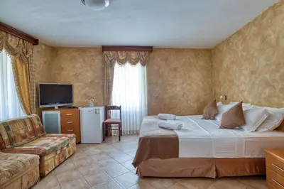 a bedroom with a bed and a couch and a television at Hotel Rendez Vous in Kotor