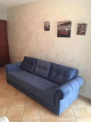 a blue couch in a living room with pictures on the wall at Impuls 2 in Budva
