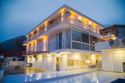 a large white building with a pool in front of it at Vila Nikezić in Sutomore