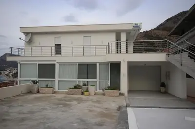 a large white building with a balcony and stairs at Vila Nikezić in Sutomore