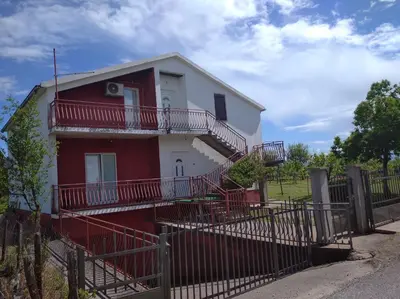 a red and white house with a fence at Airport home Radinovic in Podgorica