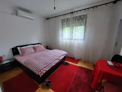 a bedroom with a bed with a red rug and a window at Airport home Radinovic in Podgorica