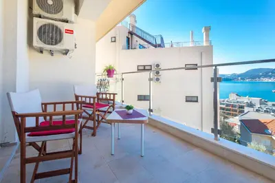 a balcony with chairs and a table and a view of the water at Belveder Apartments in Budva