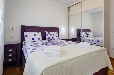 a bedroom with a large bed with a large mirror at Belveder Apartments in Budva