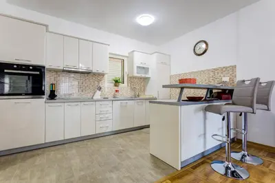 a kitchen with white cabinets and a bar stool at Belveder Apartments in Budva