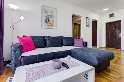 a living room with a blue couch and pink pillows at Belveder Apartments in Budva