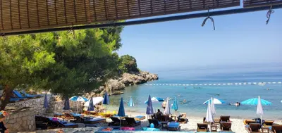 a beach with umbrellas and chairs and the ocean at Majero Apartments in Utjeha