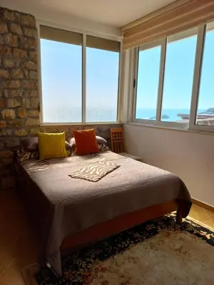 a bedroom with a bed with three pillows and windows at Apartments Antigona Old Town in Ulcinj