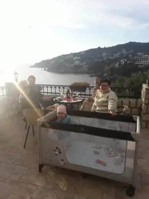 a group of people sitting around a table with a baby in a crib at Apartments Antigona Old Town in Ulcinj