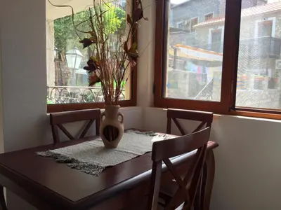 a dining room table with a vase on it with two windows at Apartments Antigona Old Town in Ulcinj